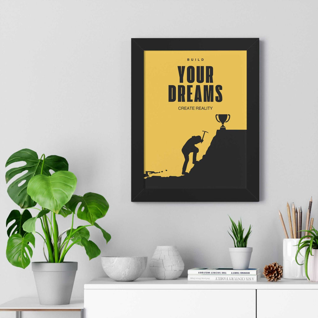Framed Build & Create motivational poster with silhouette climbing hill toward trophy on yellow background displayed above white shelf with plants and decor items