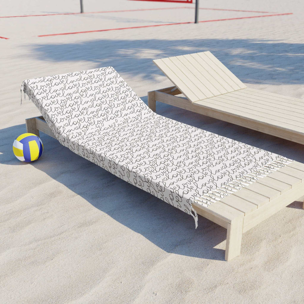 Love Beach Cloth with black script text pattern on a wooden lounge chair at the beach