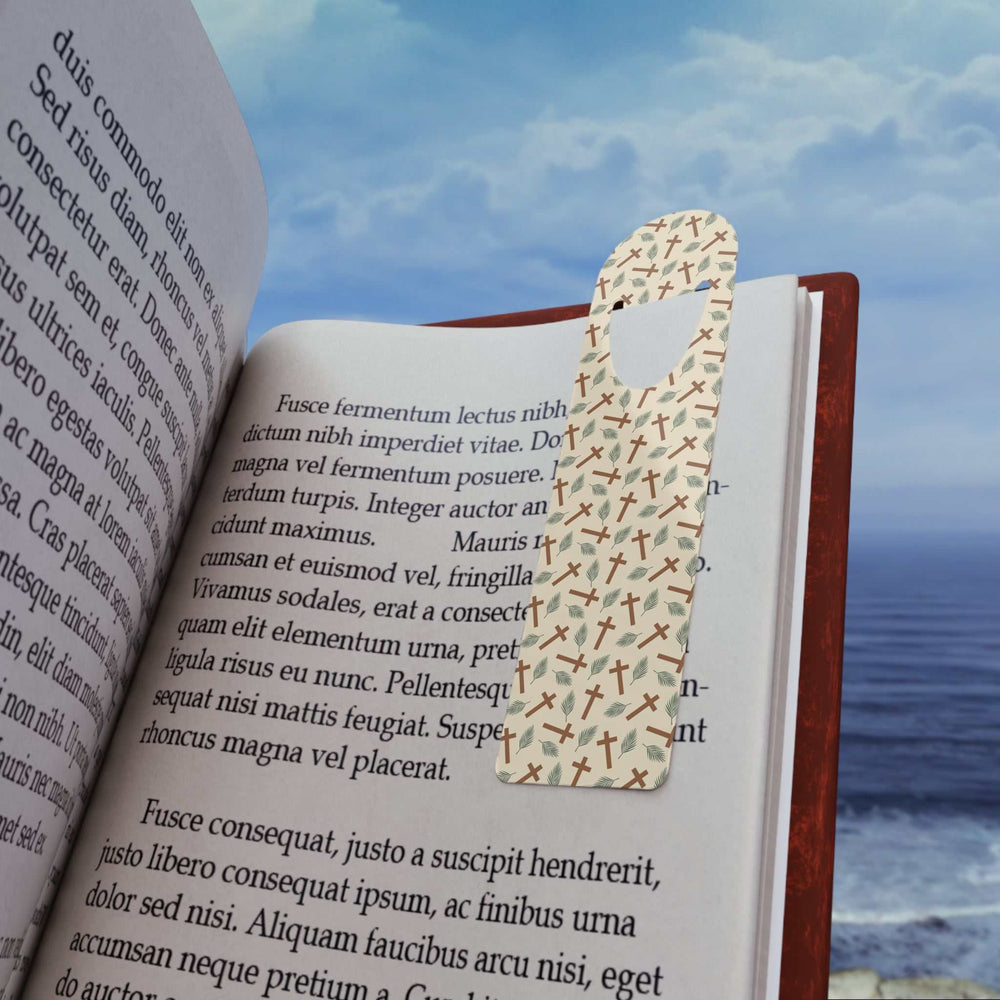 Faith Cross Bookmark with cross pattern on aluminum holding a book page against ocean background