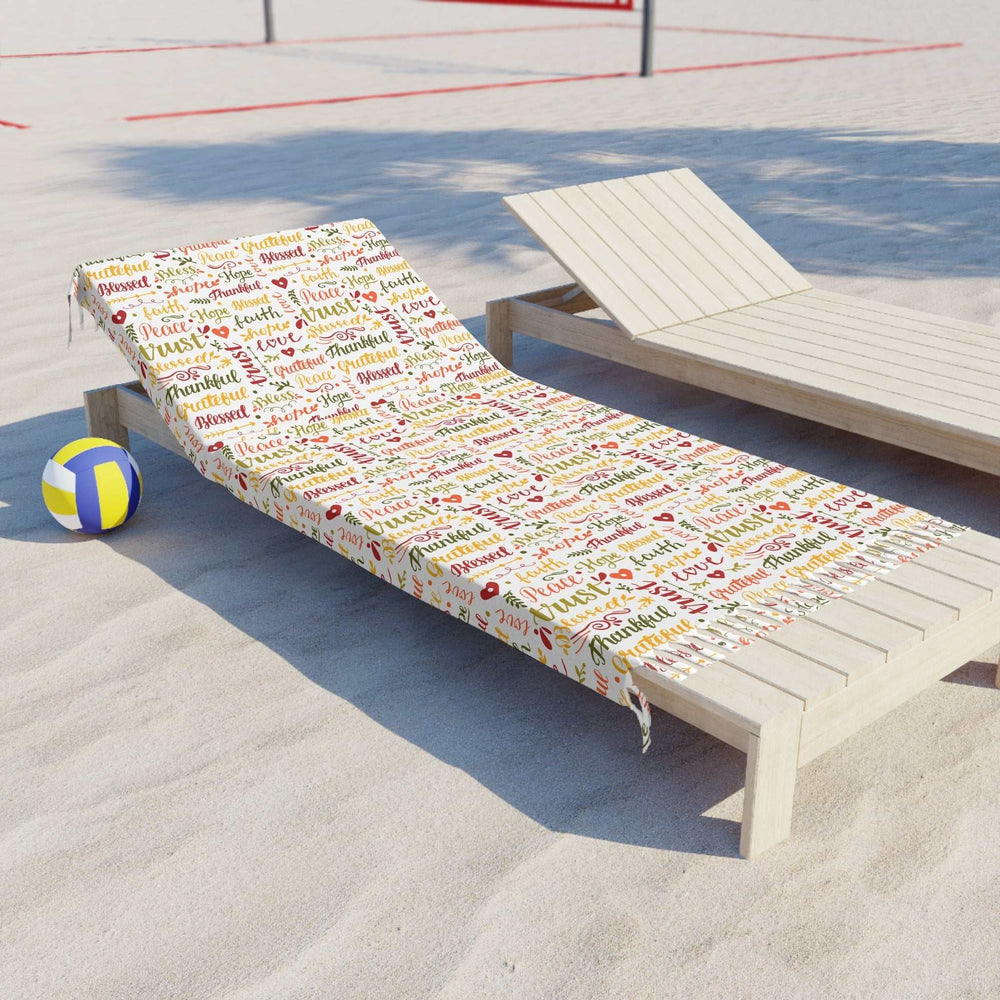Christian Beach Cloth with colorful Christian-themed words and knotted tassels on a beach lounge chair