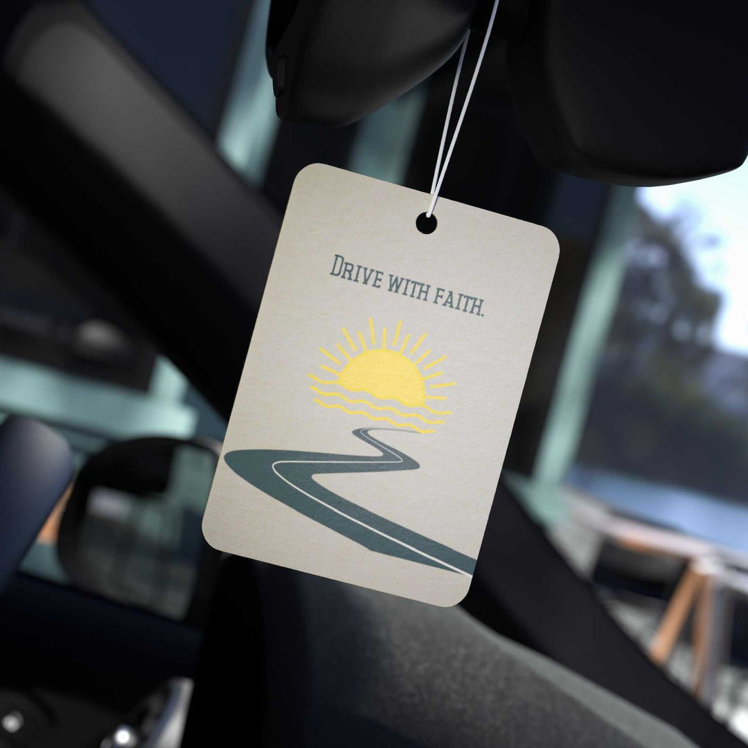 Drive With Faith car air freshener hanging in car with sun and road design, available in Pine, New Car, and Black Ice scents