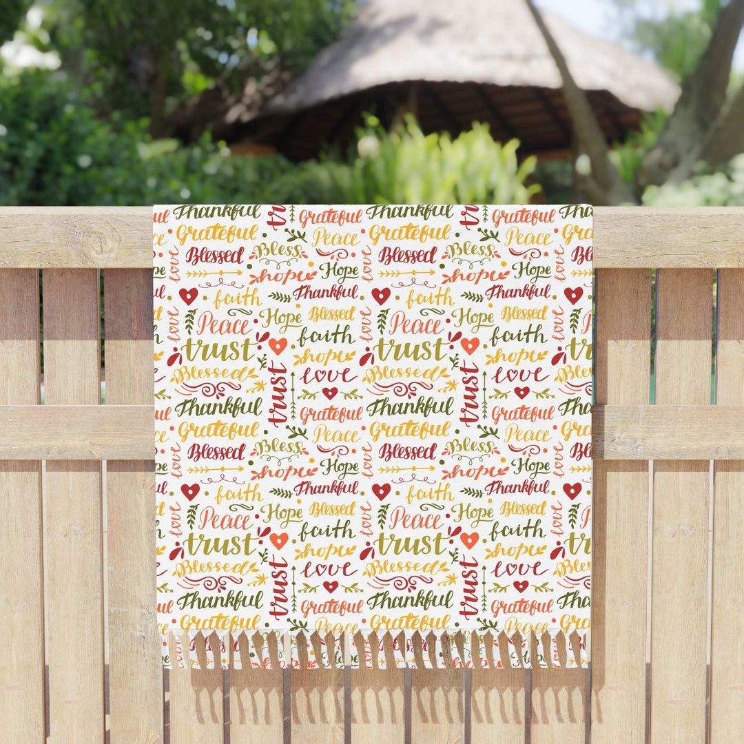 Christian Beach Cloth with colorful faith-inspired words and knotted tassels on edges displayed on wooden fence outdoors