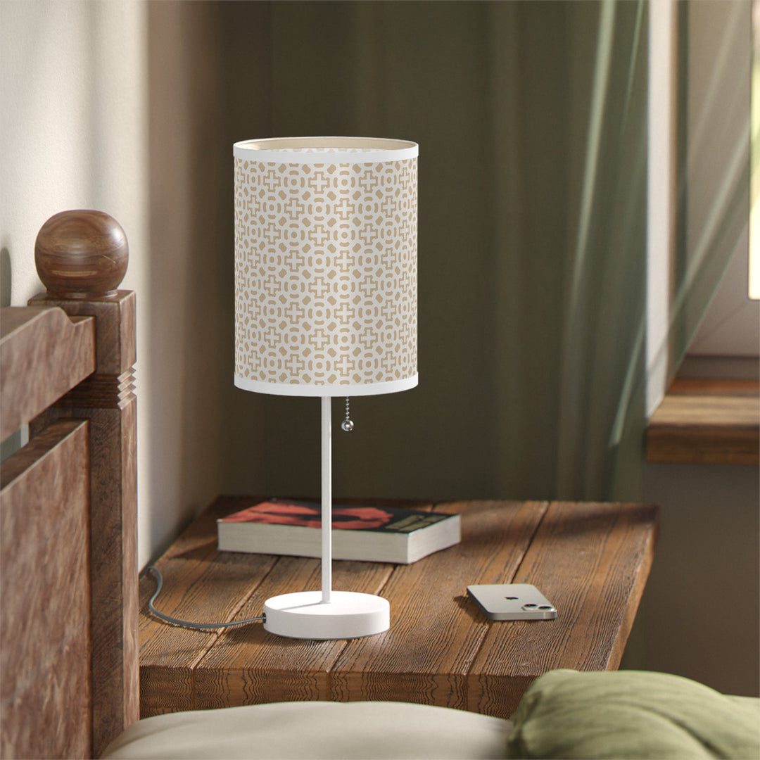 White cross design lamp with steel base on wooden bedside table next to window