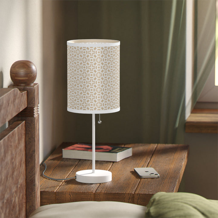 White cross design lamp with steel base on wooden bedside table next to window