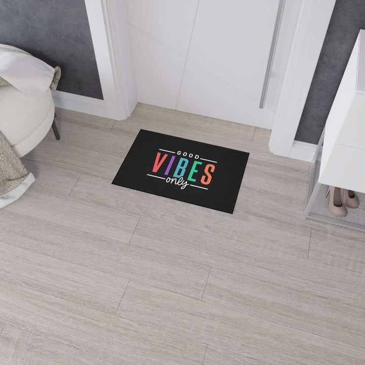 Good Vibes Floor Mat with colorful text, black trim, non-slip backing on light wood floor near door