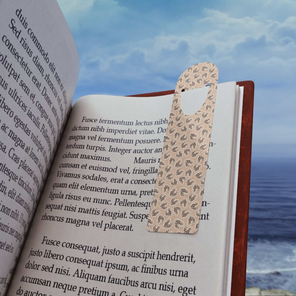 Leopard Hearts Bookmark aluminum page holder with leopard print design in an open book by the sea