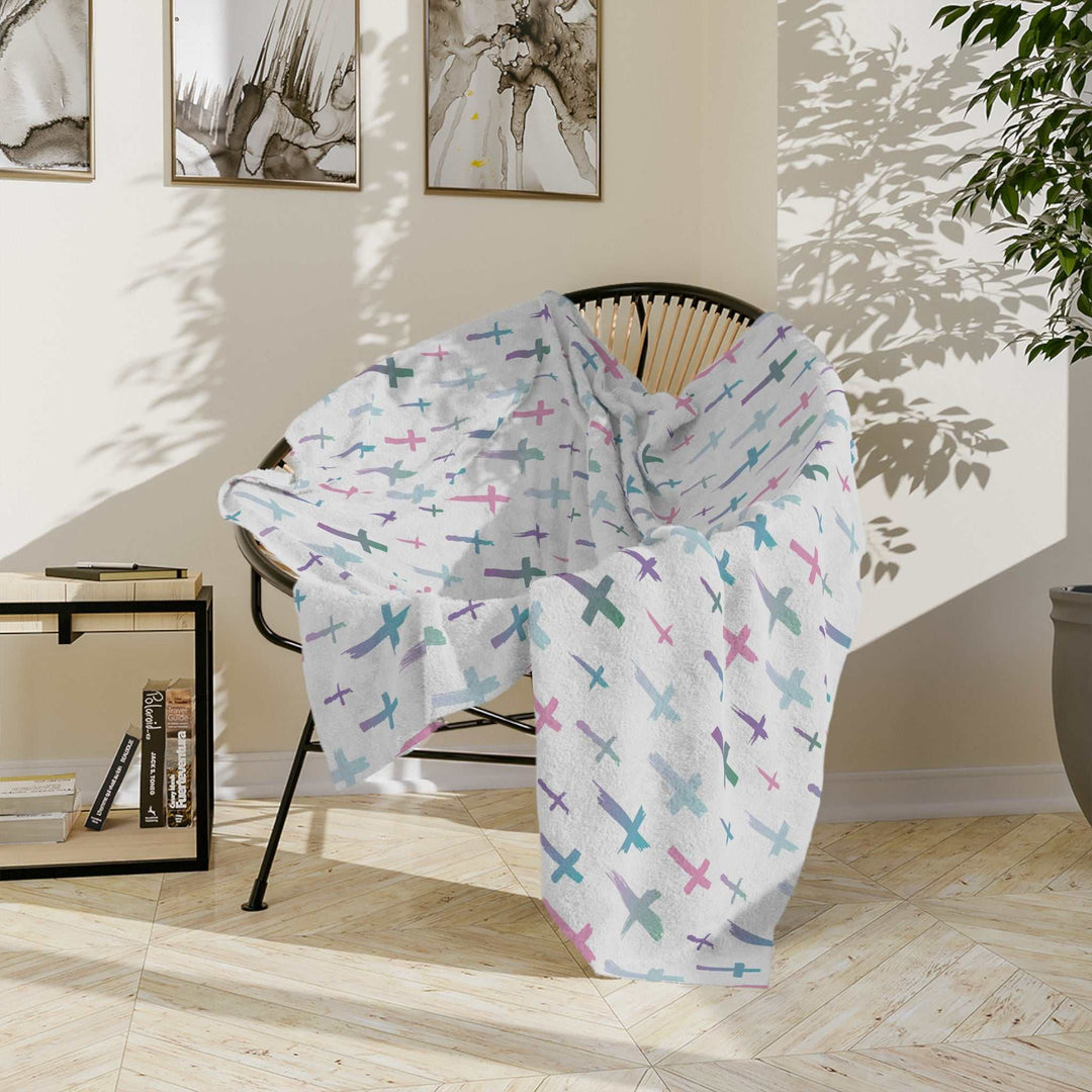 Christian Cross Blanket with pastel cross pattern draped over chair in cozy living room setting