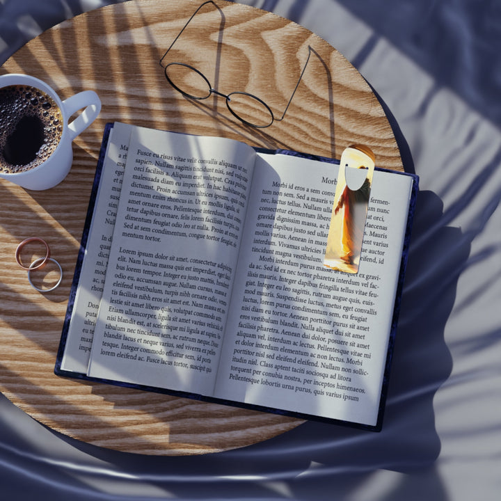 Jesus Christ metal bookmark clipping open book on wooden table with coffee and glasses in sunlight shadows