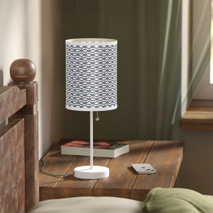 Christian design lamp with steel white base and fish pattern shade on wooden bedside table