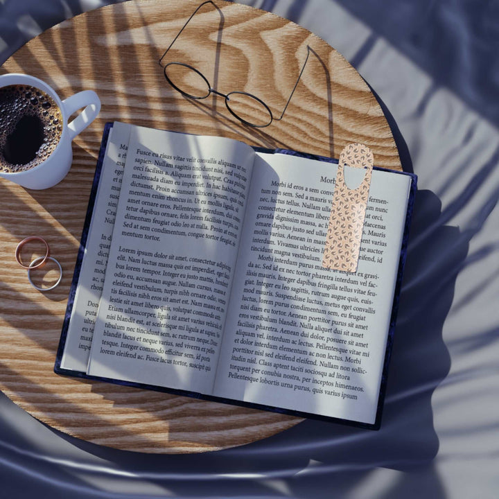 Aluminum Leopard Hearts Bookmark with top slot on open book on wooden table with glasses and coffee cup