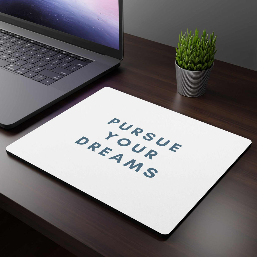 Follow Dreams Mouse Pad with white cloth top and non-slip rubber backing on office desk next to laptop and plant