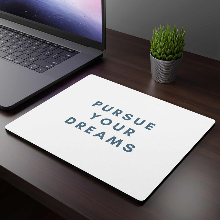 Follow Dreams Mouse Pad with white cloth top and non-slip rubber backing on office desk next to laptop and plant