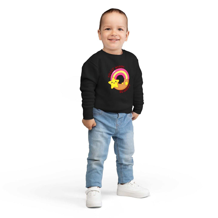 Toddler wearing black Donut Worry sweatshirt with colorful rainbow and star design, paired with light blue jeans and white sneakers