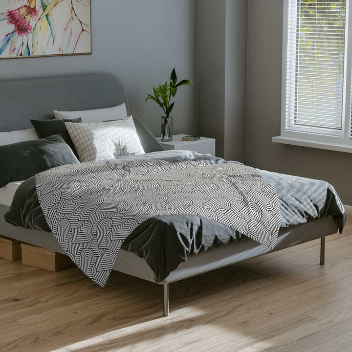 Cozy fleece blanket with black and white geometric heart pattern on modern bed in bright bedroom