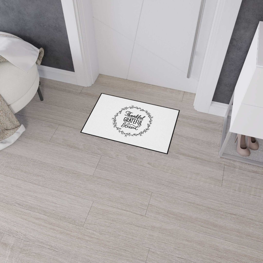 Inspirational floor mat with grateful quote and black trim on light hardwood floor