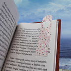 Colorful aluminum bookmark with heart design holding page in open book on ocean background