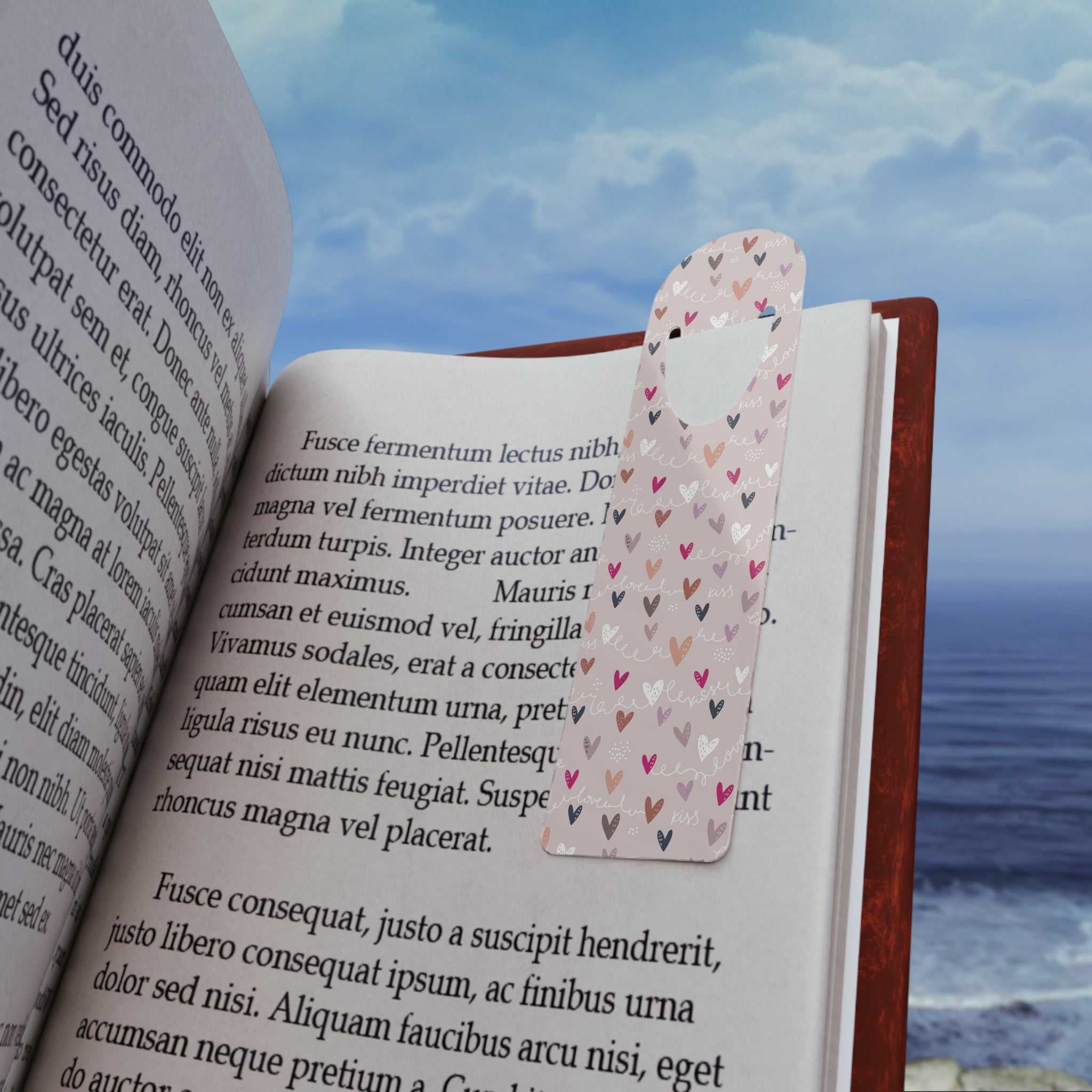 Colorful aluminum bookmark with heart design holding page in open book on ocean background