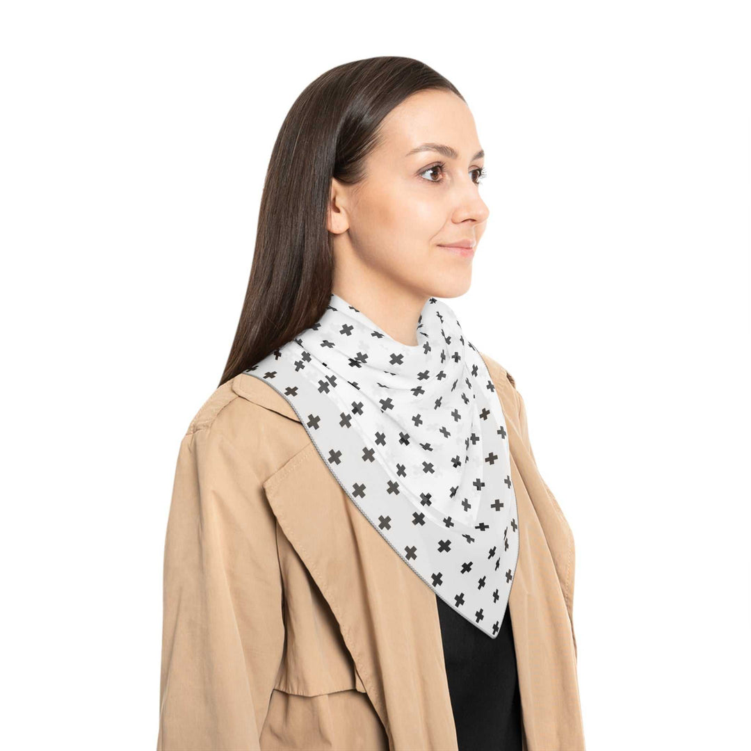 Woman wearing a lightweight sheer Christian Poly Scarf with black cross print and black stitching, styled with a beige jacket