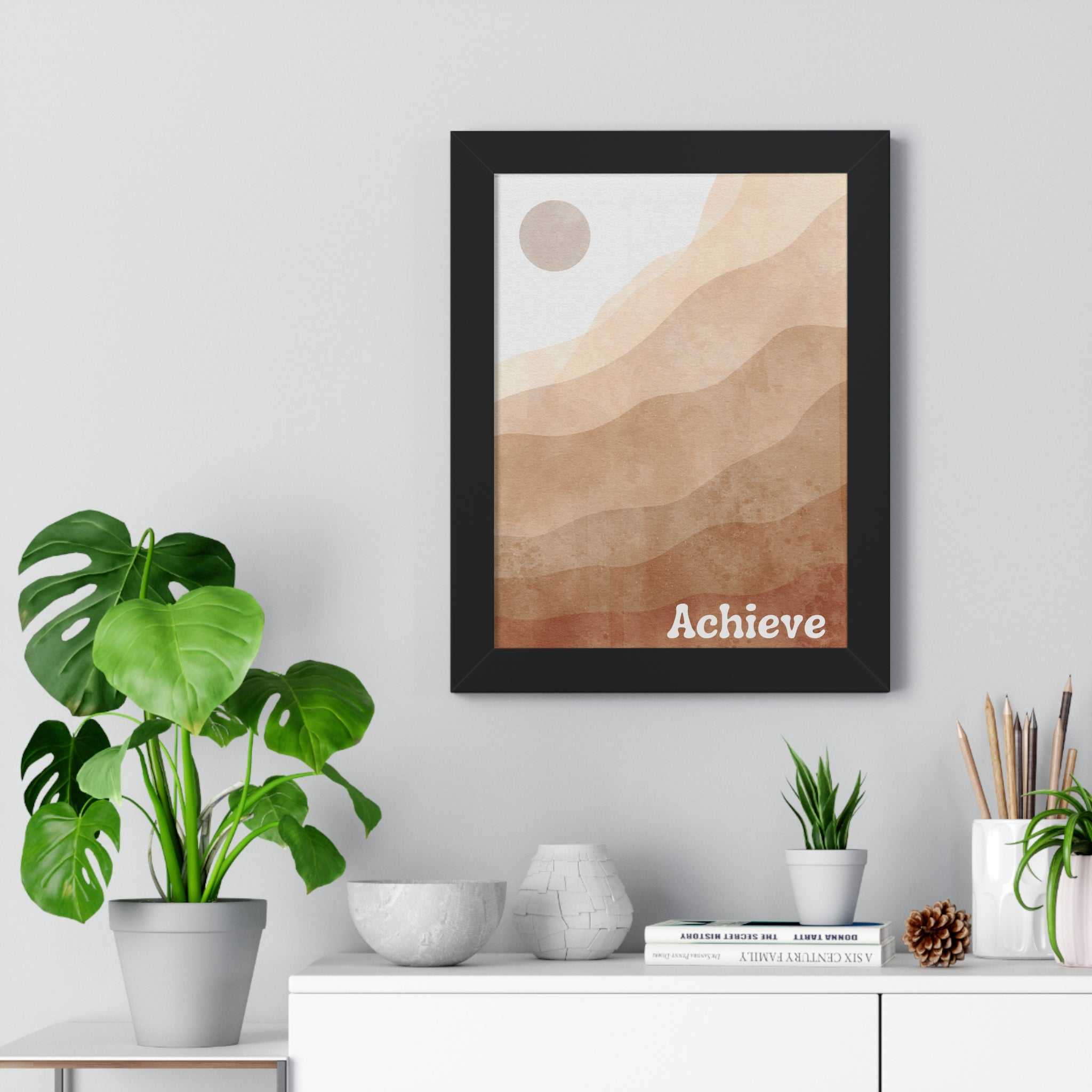 Achieve framed poster with motivational design in neutral tones displayed on wall above white shelf with plants and decor