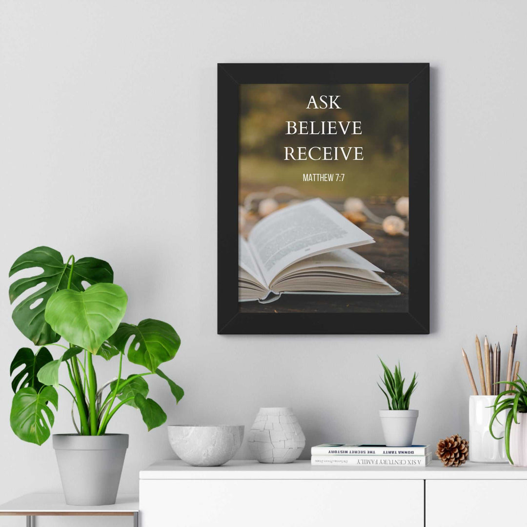 Inspirational Ask Believe Receive poster with open book and Bible verse Matthew 7:7 in black frame on wall above modern white shelf with green plants and decor