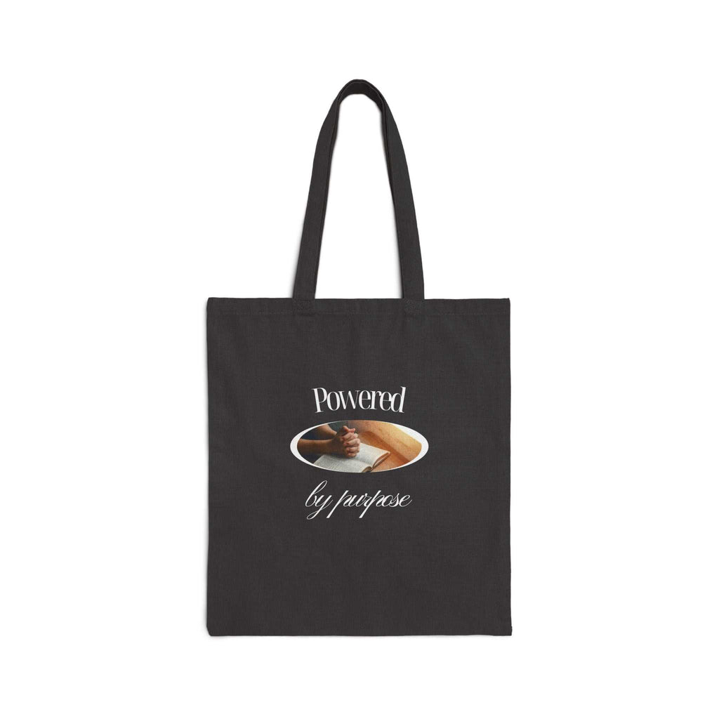 Black cotton canvas tote bag with "Powered by purpose" text and clasped hands design, eco-friendly and durable.