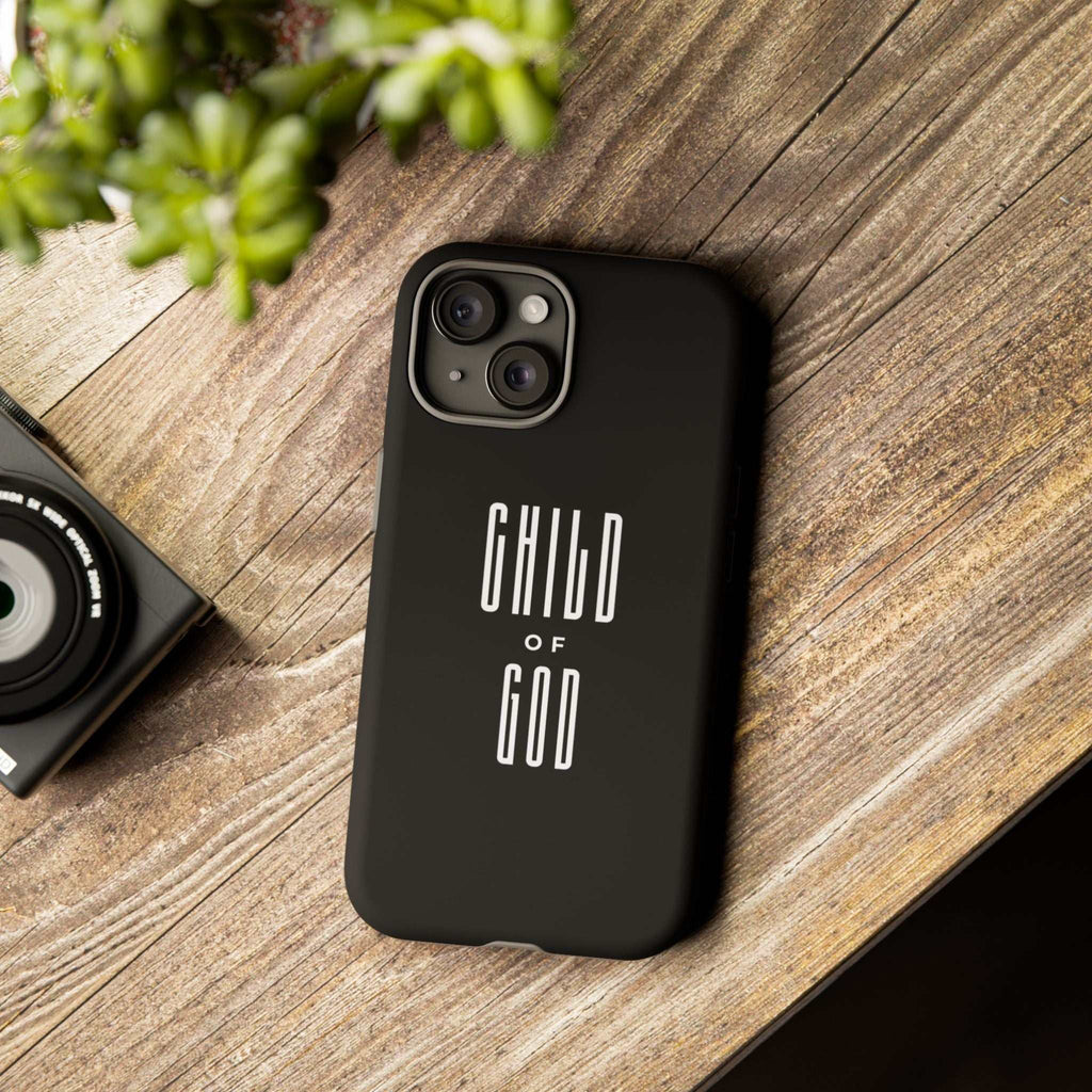 Black "Child of God" phone case with matte finish on wooden surface, durable dual-layer protective phone case