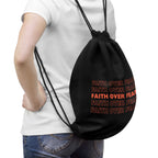 Black drawstring bag with repeated "Faith Over Fear" text in bold orange, worn on back
