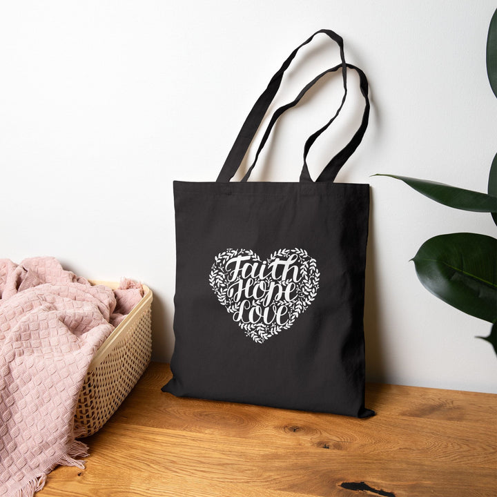 Black inspirational tote bag with "Faith Hope Love" heart design
