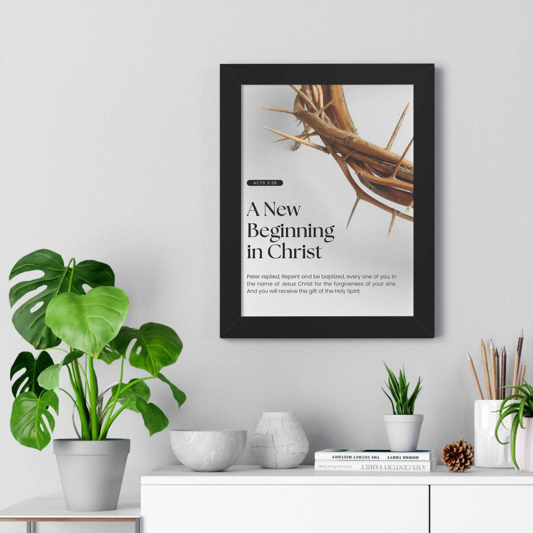 Framed Born Again poster with crown of thorns and text "A New Beginning in Christ" hanging above white cabinet with plants and decor