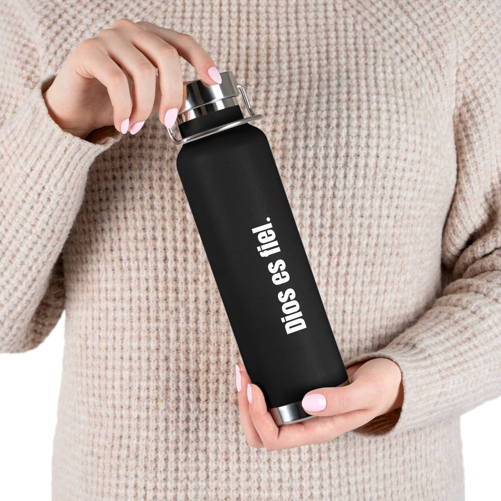 Black Dios Es Fiel bottle with silver lid held by person wearing beige sweater