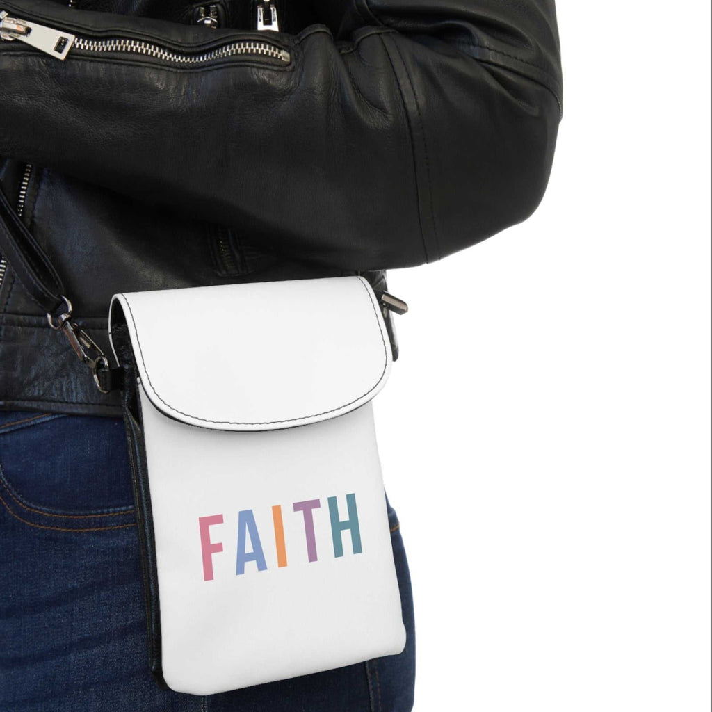 White faux leather cell phone wallet with colorful FAITH text and adjustable strap worn crossbody