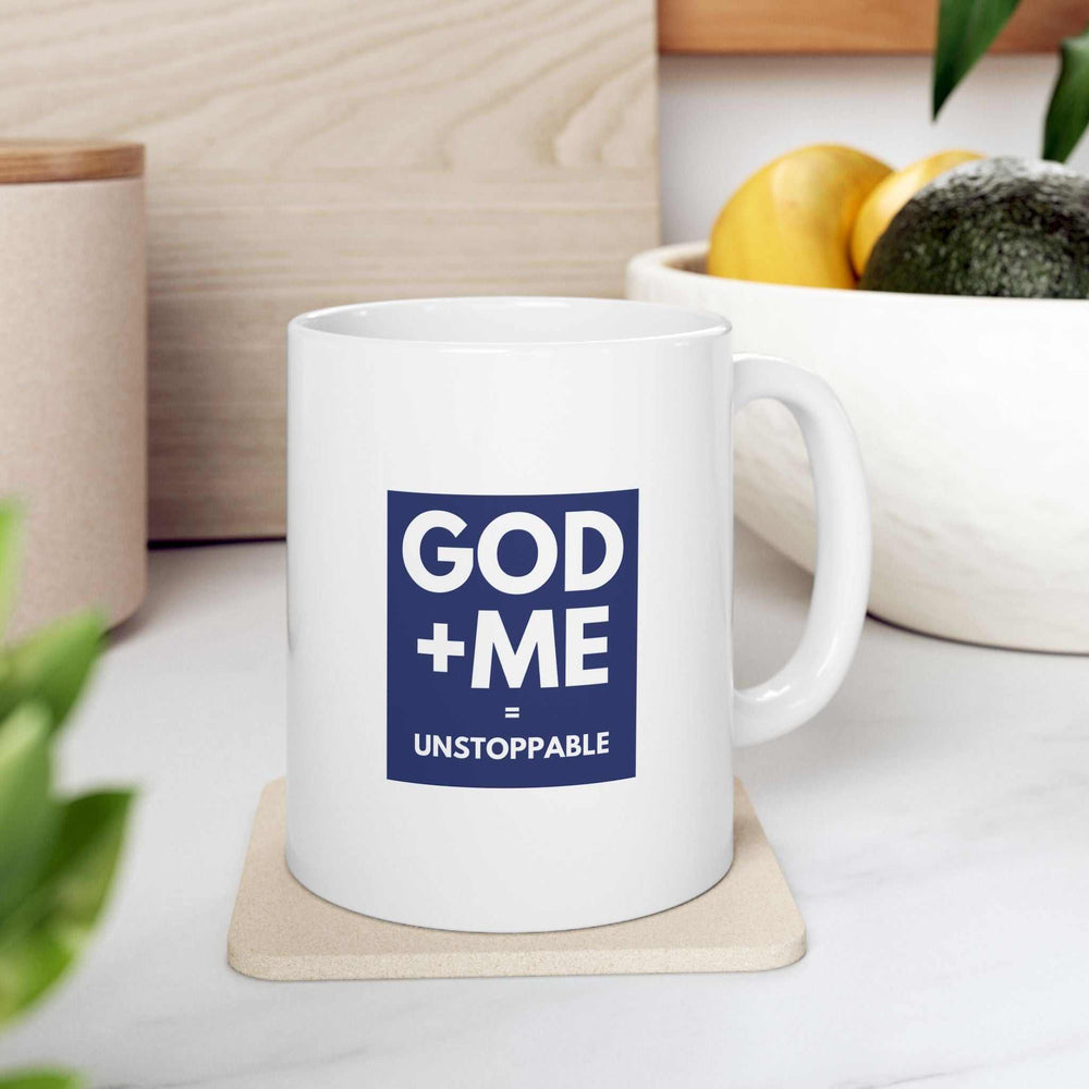 White ceramic mug with "GOD + ME = UNSTOPPABLE" faith-based design, 11oz capacity, glossy finish, microwave and dishwasher safe.