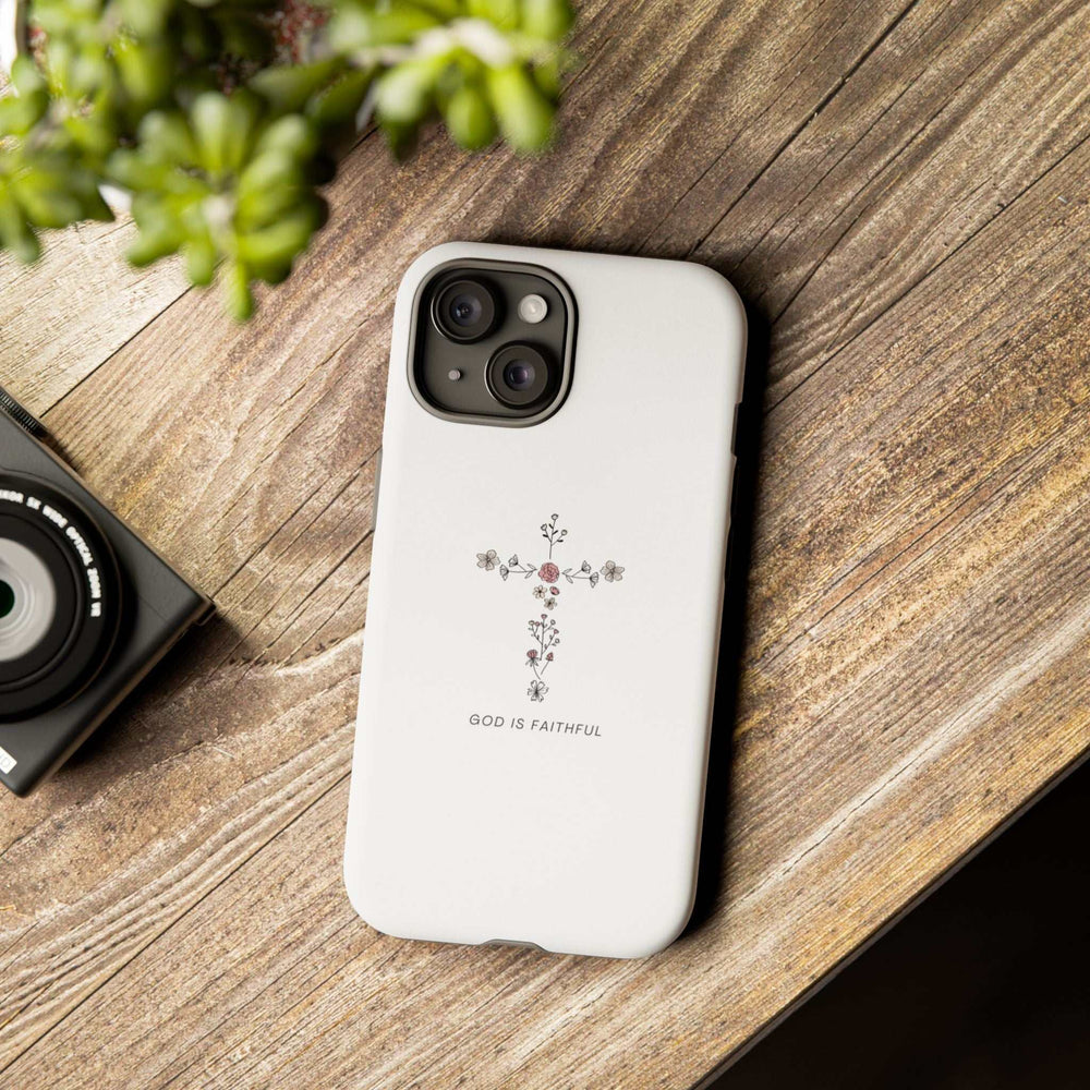 White Faithful God phone case with floral cross design and "God is Faithful" text on wooden surface