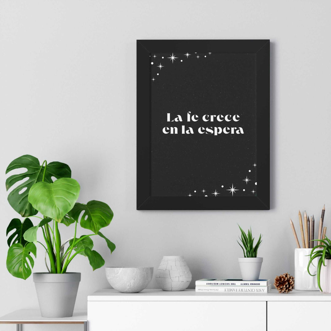Black framed Fe Que Crece poster with white Spanish text and star accents displayed above a white shelf decorated with plants and books