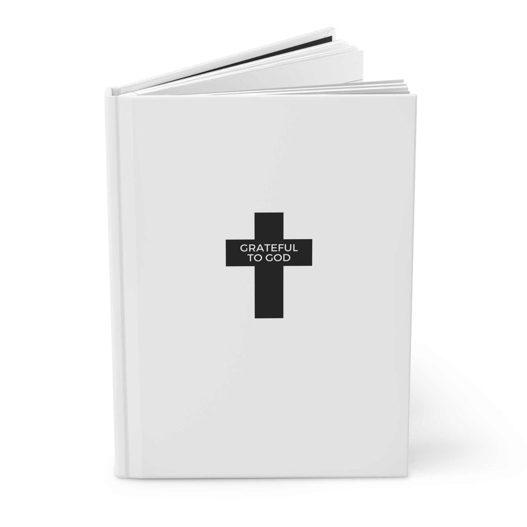 White hardcover journal with black cross and "Grateful to God" text, matte finish, lined pages for gratitude and reflection.