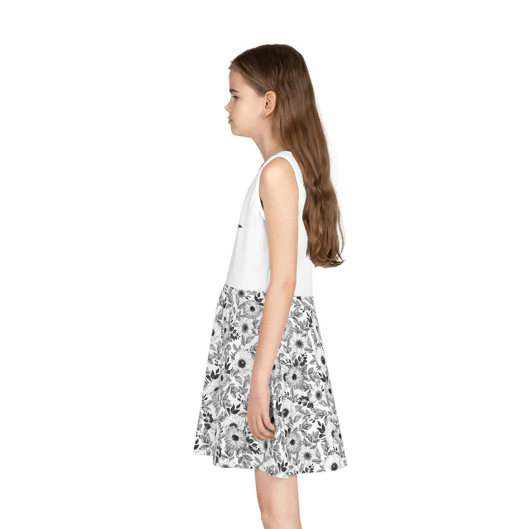 Girl wearing sleeveless sundress with white top and floral A-line skirt, mid-length design.