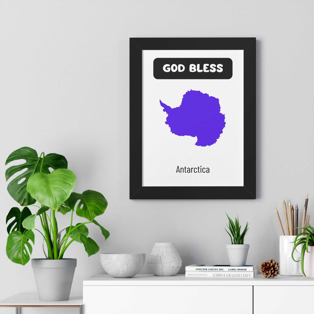 God Bless Antarctica poster with purple map design in black frame on gray wall above white shelf with green plants and decorative items