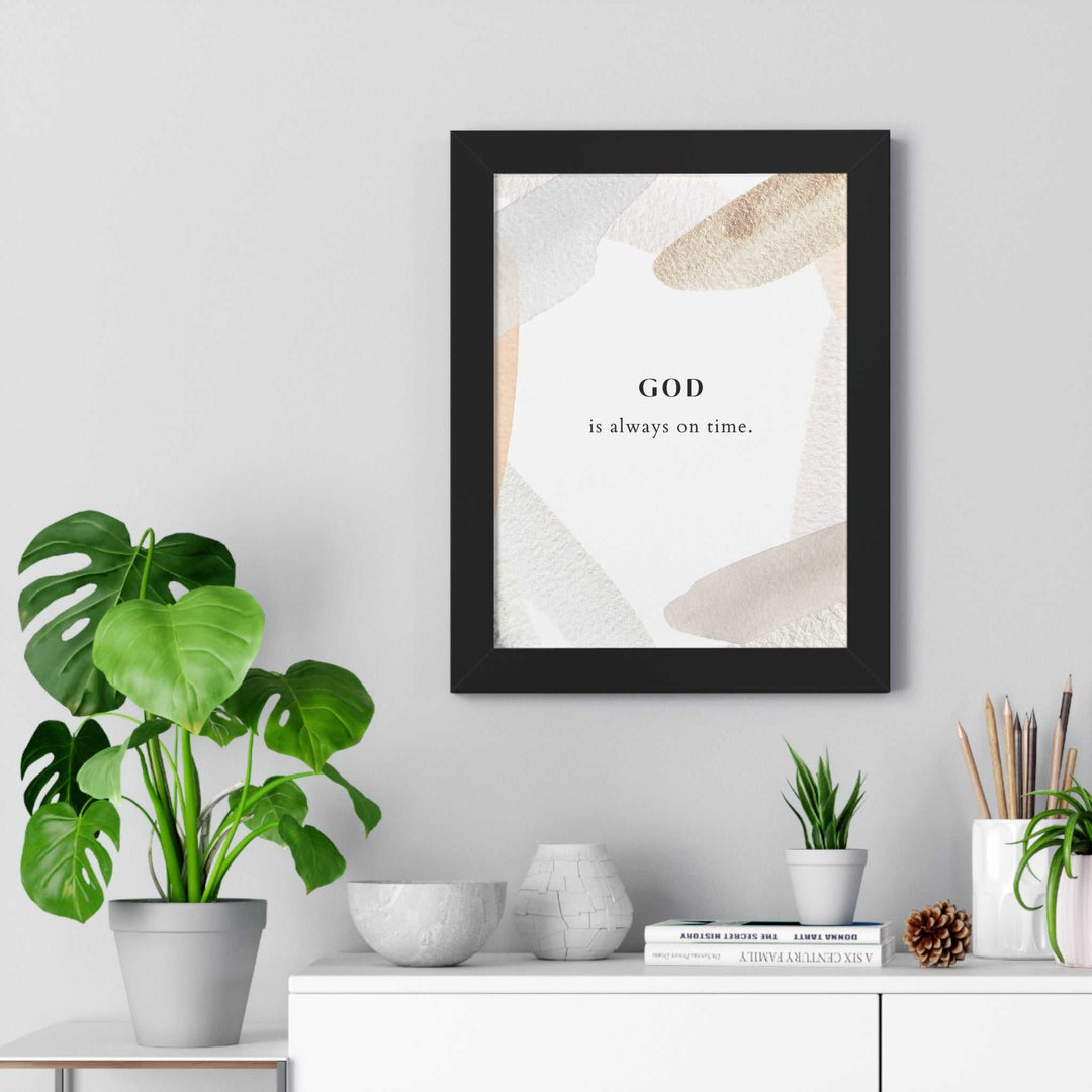 Framed God's Timing poster with inspirational faith quote "God is always on time" displayed in minimalist neutral tones on a wall above a modern white shelf with plants and decor.