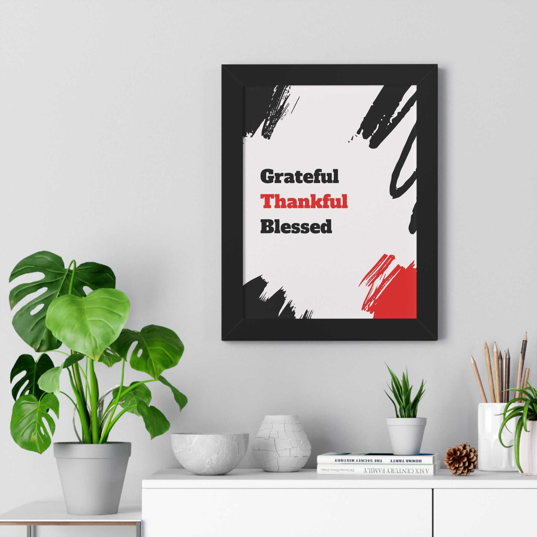 Framed poster with "Grateful Thankful Blessed" text in black and red on white background with abstract brush strokes, styled in modern home decor setting.