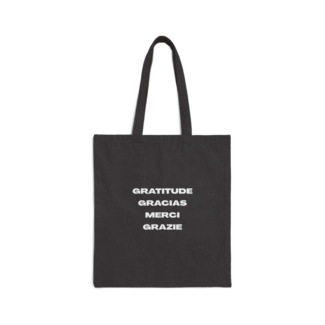 Black cotton canvas tote bag with gratitude message in multiple languages printed in white text.