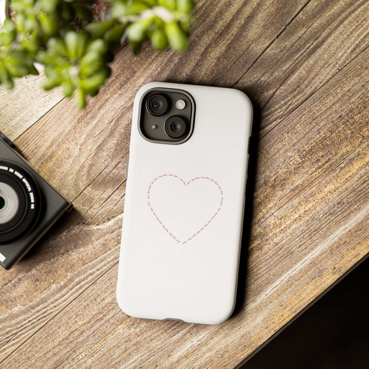 White Love Wins phone case with stitched heart design on wooden surface