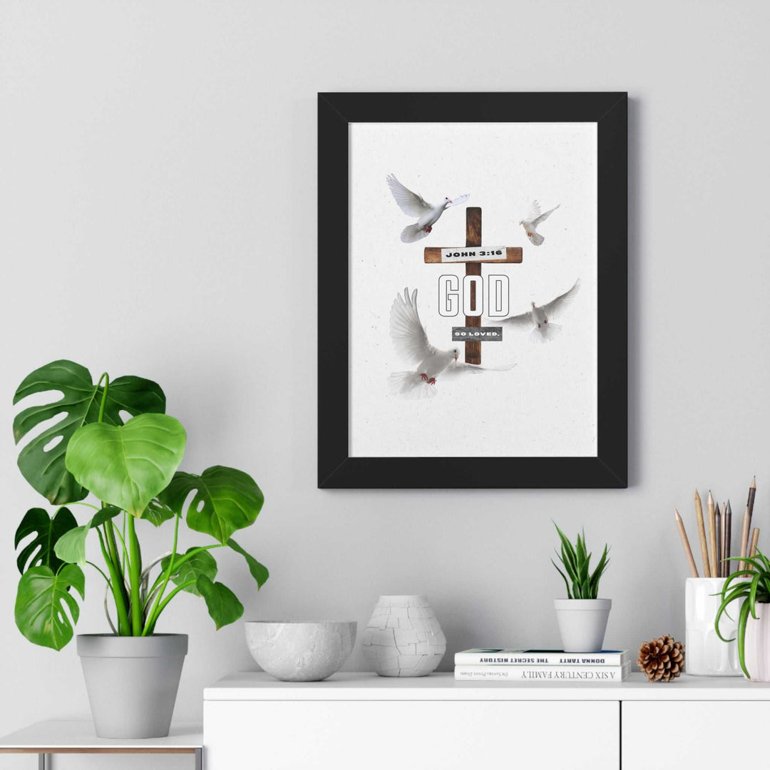 Framed "Loved" poster with doves and cross design displayed above a shelf with plants and decor