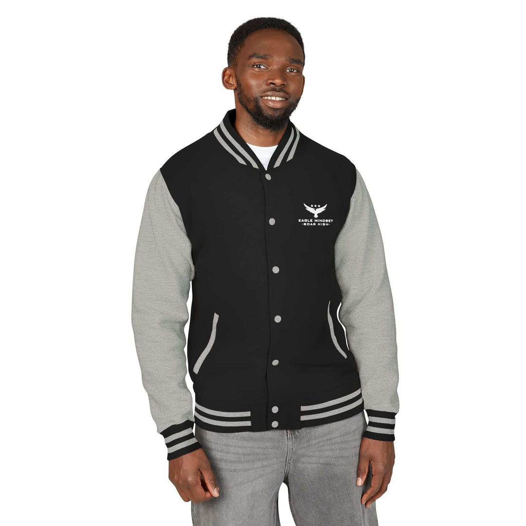 Man wearing Eagle Mindset black and grey varsity jacket with logo on chest and striped cuffs