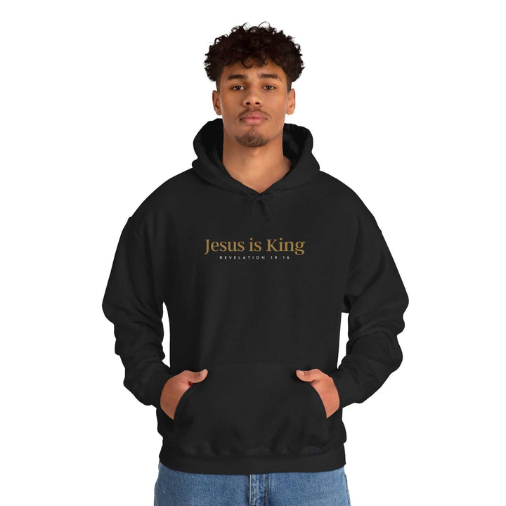 Man wearing black Jesus Is King Hoodie with gold text
