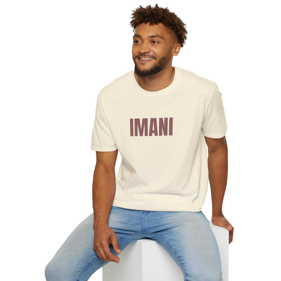 Man wearing cream Imani T-shirt with bold text, paired with light blue jeans, sitting and smiling