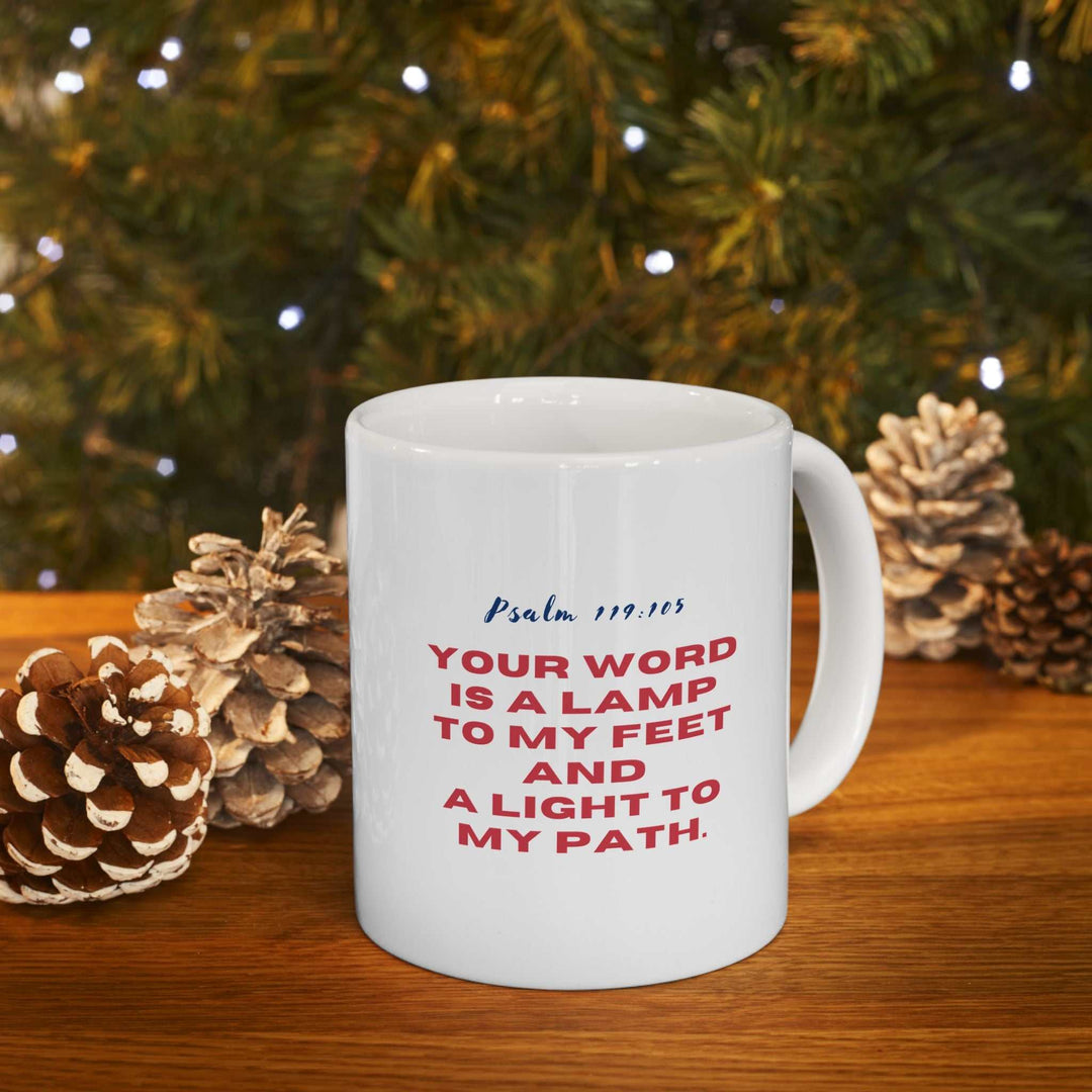 White ceramic mug with Psalm 119:105 scripture "Your word is a lamp to my feet and a light to my path" in red text, holiday pinecone background