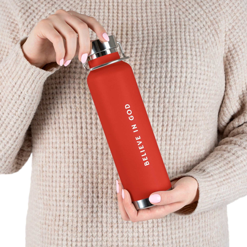 Red "Believe in God" bottle held by person wearing beige sweater, BPA-free and spill-proof design.