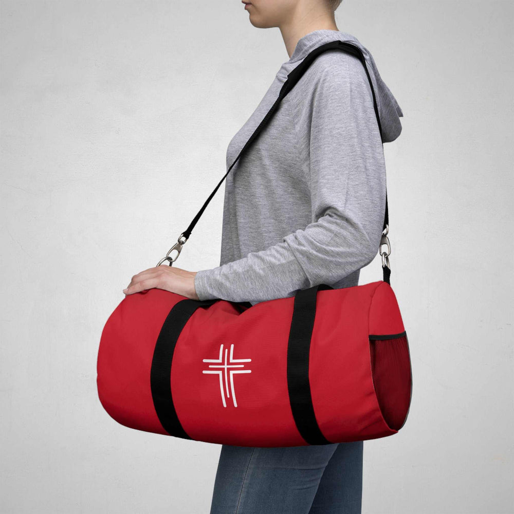 Red Christian Cross duffel bag with black straps carried on shoulder