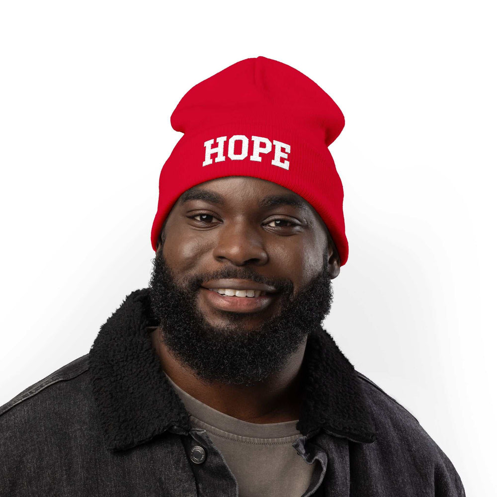 Man wearing red Hope knit beanie with white lettering and black jacket smiling