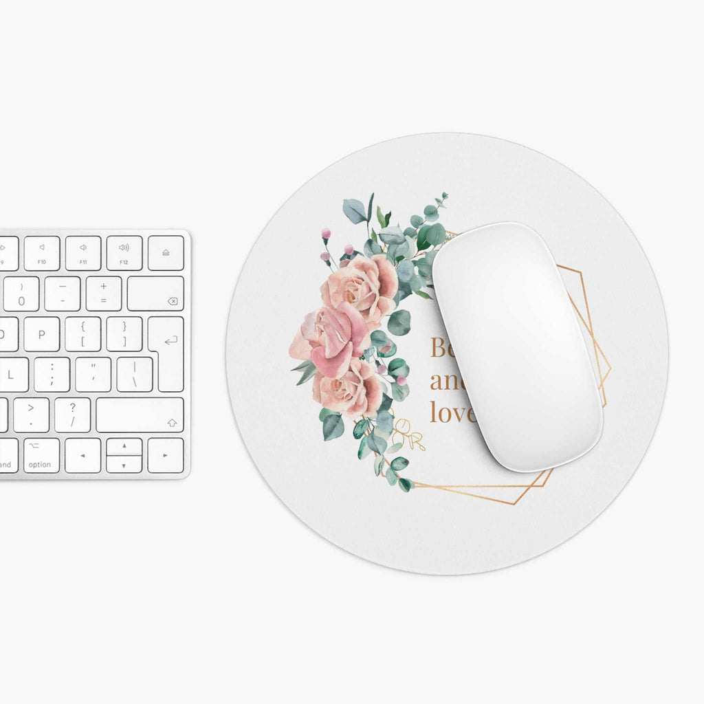 Round floral Be Kind mouse pad with inspirational message and white wireless mouse on desk next to keyboard